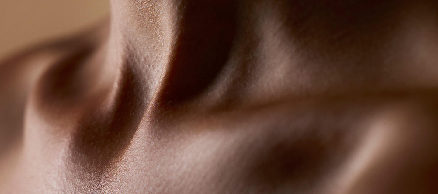 A closeup of an African-American young woman's neck with healthy skin and a beutiful play of light and shadow 